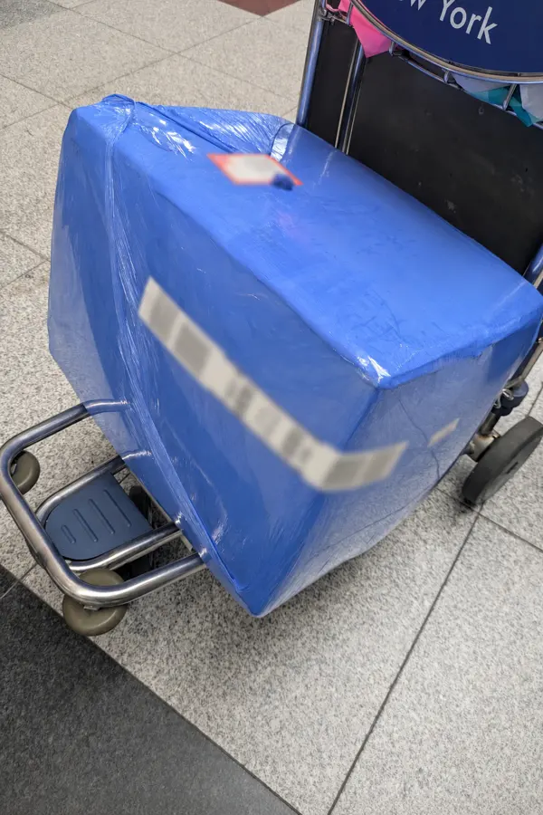 Blue wrapped OBC shipment box on an airport luggage trolley