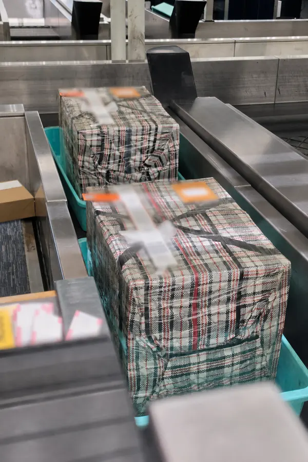 OBC shipment parcels moving along an airport baggage conveyor belt