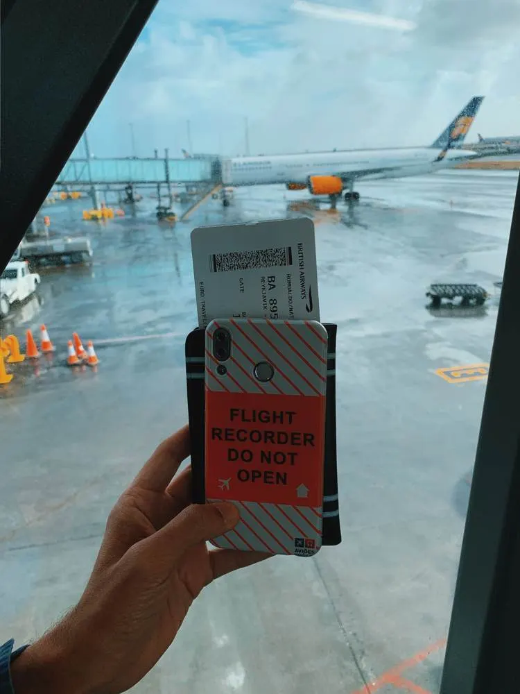 Onboard courier holding a boarding pass at the gate with an aircraft on the apron