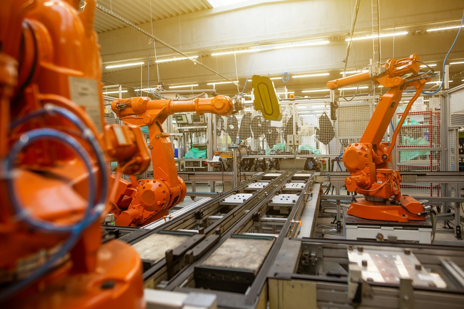 Orange robotic arms on an automotive production line.